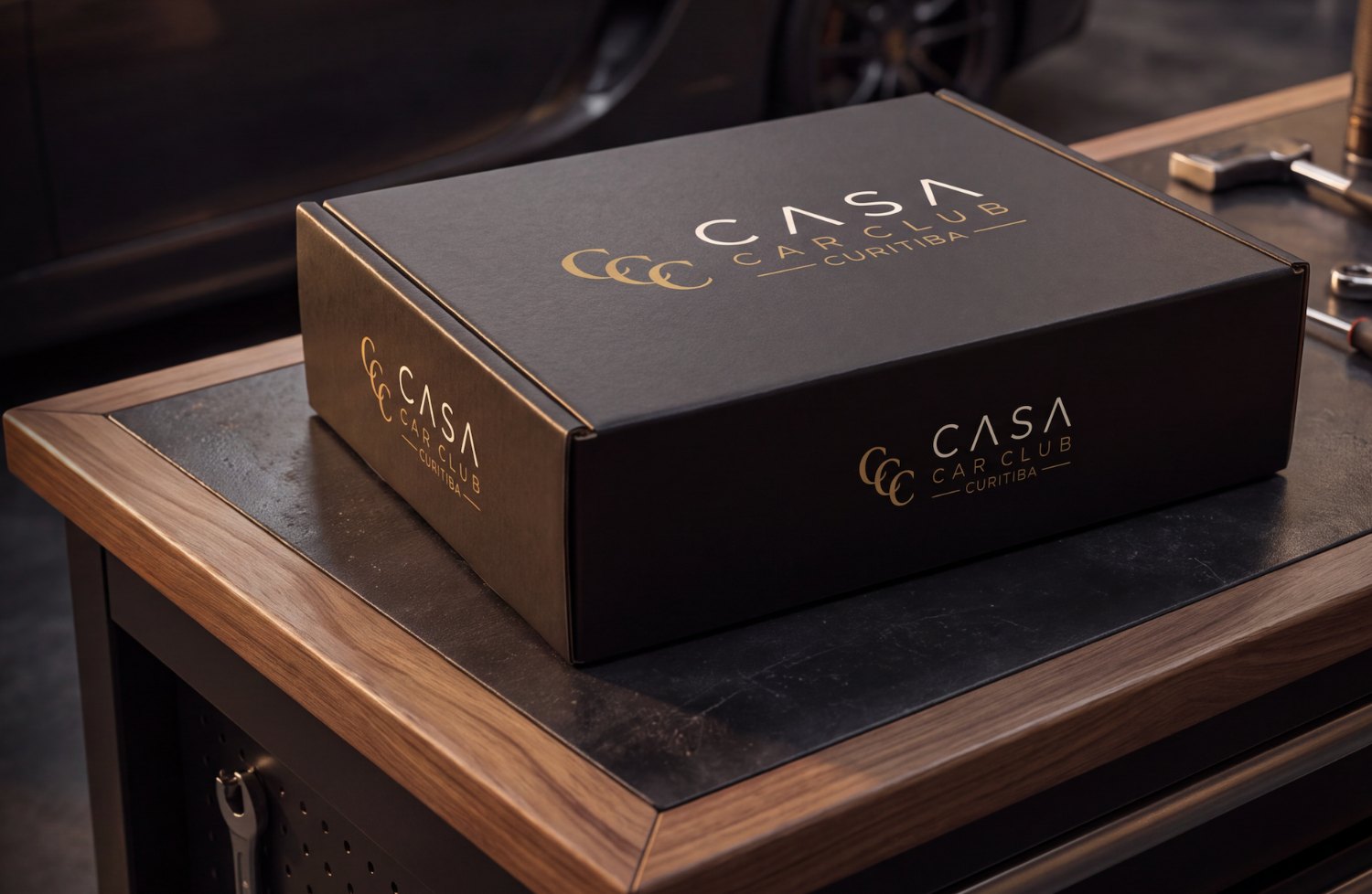 Caixa CASA Box fechada, preta com o logotipo dourado em relevo.